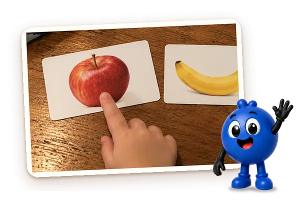 A child's finger pointing to the apple card on the table, with Milo waving